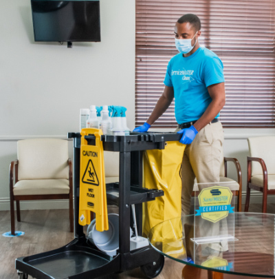 Cleaning person wheeling around a cart full of cleaning supplies in a communal waiting room