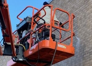 servicemaster clean employee pressure washing the side of a brick building